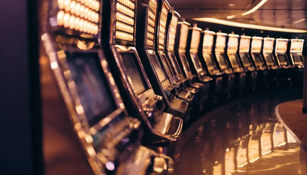 Row of illuminated slot machine cabinets on a modern UK casino floor