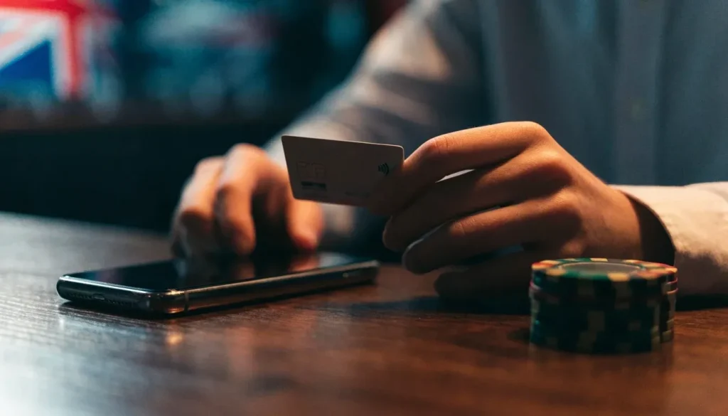 Visa debit card and closed smartphone beside casino chips